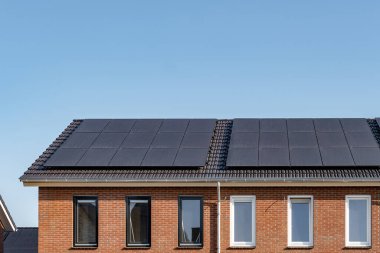 Güneşli bir gökyüzüne bağlı güneş panelleri olan yeni evler inşa edin. Siyah güneş panelleri olan yeni binaları kapatın. Zonnepanelen, Zonne enerjisi, Çevirisi: Güneş paneli, Güneş Enerjisi