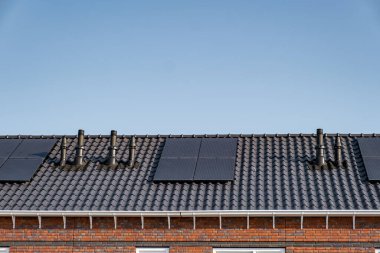 Güneşli bir gökyüzüne bağlı güneş panelleri olan yeni evler inşa edin. Siyah güneş panelleri olan yeni binaları kapatın. Zonnepanelen, Zonne enerjisi, Çevirisi: Güneş paneli, Güneş Enerjisi