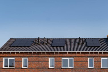 Güneşli bir gökyüzüne bağlı güneş panelleri olan yeni evler inşa edin. Siyah güneş panelleri olan yeni binaları kapatın. Zonnepanelen, Zonne enerjisi, Çevirisi: Güneş paneli, Güneş Enerjisi