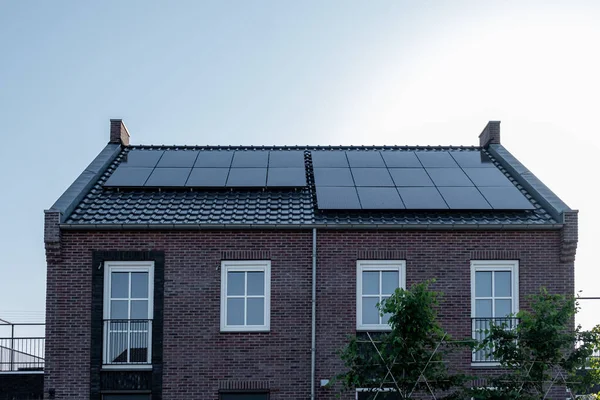 Nybyggda hus med solpaneler fästa på taket mot en solig himmel Närbild av ny byggnad med svarta solpaneler. Zonnepanelen, Zonne energie, Översättning: Solpanel,, Sun Energy — Stockfoto