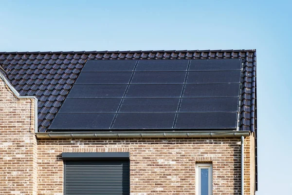 Nybyggda hus med solpaneler fästa på taket mot en solig himmel Närbild av ny byggnad med svarta solpaneler. Zonnepanelen, Zonne energie, Översättning: Solpanel,, Sun Energy — Stockfoto