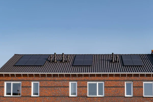 Nybyggda hus med solpaneler fästa på taket mot en solig himmel Närbild av ny byggnad med svarta solpaneler. Zonnepanelen, Zonne energie, Översättning: Solpanel,, Sun Energy — Stockfoto