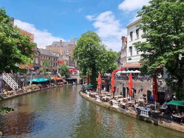 Utrecht 'te yaz mevsimi, Hollanda' nın Utrecht, Hollanda 'nın merkezindeki Oudegracht Eski Kanalı' ndaki geleneksel evler, terasta yaşayan insanlarla birlikte..