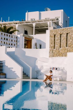 Sonsuz yüzme havuzunda dinlenen, okyanusa bakan, havuzda havuz başında kitap okuyan genç bir kız.