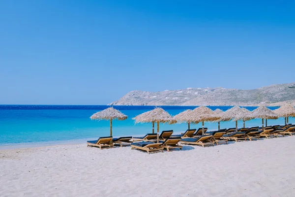 Mykonos 해변의 젊은 남자 , Elia 해변 Mikonos, 여름 동안에는 Mykonos 해변에 우산 과 고급 해변 의자가 있는 침대 , Elia 해변 Mikonos 그리스의 푸른 바다 — 스톡 사진