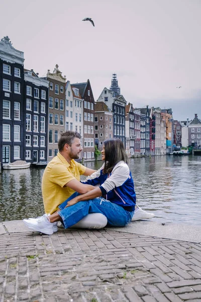 Amsterdam Holandia, szczęśliwa para mężczyzna i kobieta w letni wieczór nad kanałami Amsterdamu. Mężczyzna i kobieta w średnim wieku Azjatka dziewczyna i europejscy mężczyźni na wakacjach — Zdjęcie stockowe