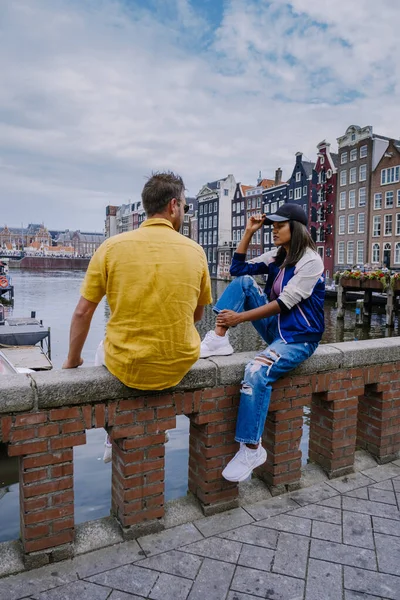 Amsterdam Nederland, gelukkig stel man en vrouw op een zomeravond aan de grachten van Amsterdam. man en vrouw middelbare leeftijd aziatisch meisje en Europese mannen op citytrip — Stockfoto