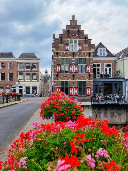 네델 란 드 운하에 있는 집들, 배들 및 나무들. 앞쪽에 꽃이 피고 뒤에 구름 이 있는 푸른 하늘 이 있다. 고린 켐 시, 네덜란드. — 스톡 사진
