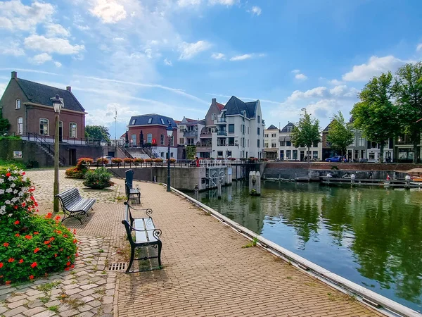 Huizen, Boten en bomen op het Nederlandse Kanaal. Met bloemen op de voorgrond en een blauwe lucht met wolken op de achtergrond. Gemeente Gorinchem, Nederland. — Stockfoto