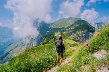 Sırt çantalı bir kadın dağın tepesinde durur, güzel yerlere seyahat eder, hedefe ulaşır, Saxer Luecke 'de dağ sırtı, Alpstein Appenzell Innerrhoden İsviçre' de Kreuzberge 'de.