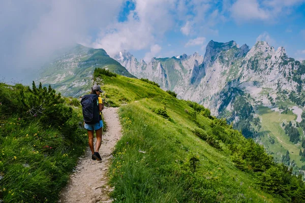 A woman with a backpack stands on top of a mountain , The girl travels to beautiful places, Reaching the goal, mountain ridge at Saxer Luecke , Kreuzberge in Alpstein Appenzell Innerrhoden Switzerland — Stock Photo, Image