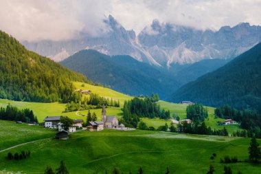 Val di Funes 'deki Santa Magdalena köyü İtalyan Dolomitleri üzerinde. Arka planında renkli ağaçlar ve Odle Dağı grubu olan vadinin sonbahar manzarası. İtalya