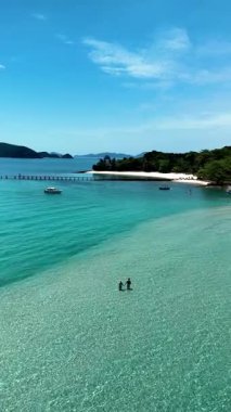 Koh Kham Island, where crystal-clear waters meet soft sandy beaches. This tropical paradise invites relaxation and adventure, a couple of caucasian men and Asian women on vacation