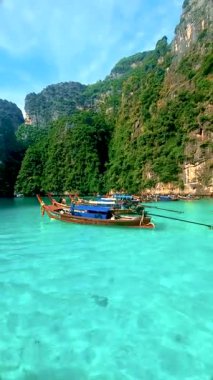 Muhteşem kireçtaşı kayalıklarıyla çevrili Tayland 'ın berrak sularının nefes kesici manzarası. Geleneksel tekneler canlı mavi denizde süzülerek Koh Phi Phi Gölü 'nden sakin bir kaçış sunar.