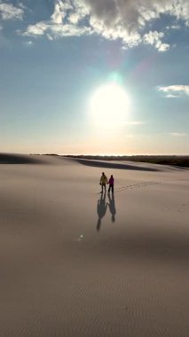 Çift, Rabjerg Mil 'in güzel kum tepelerinde el ele yürür, nefes kesici bir günbatımı ile gökyüzünü aydınlatır. Bu huzurlu an, doğanın ve romantizmin özünü yakalar..