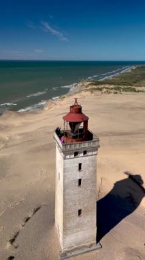 Rubjerg Knude Deniz Feneri Kuzey Denizi kıyısında muhteşem bir şekilde duruyor, kumlu sahilde gölgeler bırakıyor. Ziyaretçiler kıyı şeridinin nefes kesici manzarasına ve sahile vuran sakin dalgalara hayran kalabilirler..