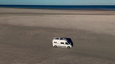 Huzurlu bir gün geçirin Lakolk Strand, Romo, Danimarka 'da, sakin okyanus dalgaları ve açık alanlarla çevrili engin kumlu sahilde bir karavan park eder..