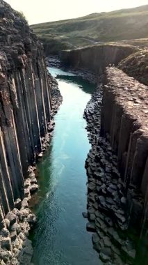 Studlagil Kanyonu 'nun nefes kesici güzelliğine hayret ediyorum. Bazalt sütunları turkuaz sulardan çarpıcı bir şekilde yükseliyor. Bu İzlanda mücevheri doğasını ve çekiciliğini sergiliyor.