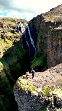İki yürüyüşçünün dramatik bir kanyonun kenarında durduğu İzlanda 'daki Glymur Şelalesi' nin nefes kesici güzelliğini tecrübe edin..