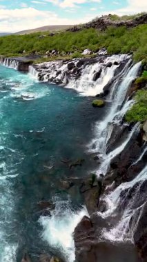 İzlanda 'daki hayret verici Hraunfossar şelalesini keşfedin. Kristal berrak suların kayalık arazide aktığı yer..
