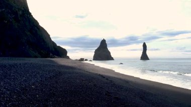 Reynisfjara kara kumsalında eşsiz bazalt sütunlar ve yükselen deniz yığınları sergileniyor. Güneş batmaya başladığında dalgalar hafifçe çarpar ve doğa severler için sakin bir atmosfer yaratır..