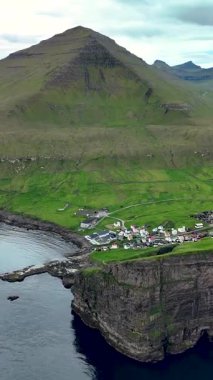 Faroe Adaları 'ndaki Gjogv' un sarp kayalıkların ve canlı yeşil tepelerin arasına kurulmuş pitoresk köyünü keşfedin. Doğa bu huzurlu yerde gelişiyor..