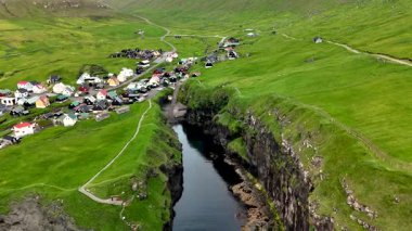 Yeşil tepelerin dramatik uçurumların yakınında büyüleyici evlerle buluşması gibi Faroe Adaları 'nın güzelliğini tecrübe edin. Manzaralı nehir manzaranın içinden akar, Gjogv köyü