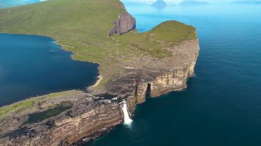 Parlak güneş ışığı altında Faroe Adaları 'nın doğal güzelliğini gözler önüne seren kayalıkların parıldayan denizin üzerinde yükseldiği Sorvagsvatn Gölü etrafındaki çarpıcı manzarayı keşfedin..