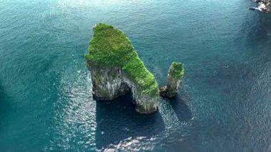 Faroe Adaları 'ndaki Drangarnir kaya oluşumlarının baş döndürücü görüntüsü. Açık bir sabahta açık mavi okyanusa karşı parlak yeşiller..