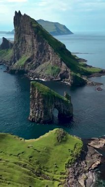 Faroe Adaları 'ndaki Drangarnir' in baş döndürücü kayalıklarını ve kaya oluşumlarını araştırın. Bu nefes kesici manzara, dingin suların arasında yükselen deniz yığınları ve yemyeşil alanlara sahiptir..