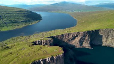 Faroe Adaları 'ndaki Sorvagsvatn Gölü' nün nefes kesici manzaralarını deneyin. Yükselen uçurumlar, yemyeşil tepeler ve sakin sular huzur verici bir ortam yaratır..