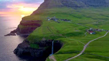 Gasadalur köyünün engebeli kıyı şeridine çarpıcı bir şekilde dalan Mulafossur Şelalesi 'ni keşfedin. Manzara nefes kesen bir gün batımıyla aydınlanıyor ve büyülü bir atmosfer yaratıyor..