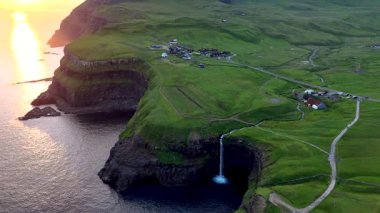 Güneş batarken Faroe Adaları 'ndaki Gasadalur köyünün sakin manzarasıyla çevrili Atlantik Okyanusu' na dökülen Mulafossur Şelalesi 'nin çarpıcı güzelliğini görün..