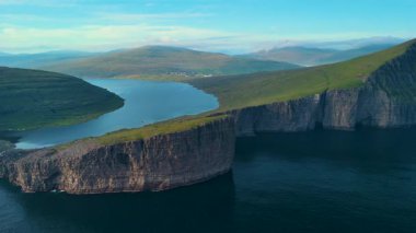 Bu büyüleyici manzara, Faroe Adaları 'ndaki okyanus kayalıklarının üzerine tünemiş Sorvagsvatn Gölü' nü gözler önüne seriyor. Huzur ve doğa, arka planda görkemli bir şekilde yükselen tepeler gibi harmanlanır..