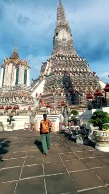 Asyalı bir kadın Tayland 'da Wat Arun' un güzelliğini keşfeder. Karmaşık mimari ve canlı renkler içerir. Ziyaretçiler tapınaklara, çarpıcı kulelere ve zengin kültür mirasına hayran.