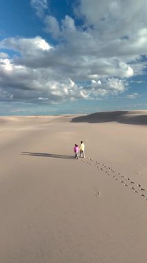 Bir aile, Danimarka 'daki Rabjerg Mile' ın çarpıcı kum tepelerinde geziniyor. Altın kumlar ve dramatik bulutlar açık hava maceraları ve rahatlama için mükemmel bir manzara yaratıyor..