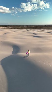 Danimarka 'daki Rabjerg Mile' ın nefes kesici güzelliğini tecrübe edin. İki kişi, parlak mavi gökyüzünün altındaki engin, yumuşak kum tepelerinde yürürken..