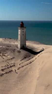 Rubjerknudde deniz feneri Kuzey Denizi 'nin arka planında gururla durur. Ziyaretçiler, Danimarka 'nın eşsiz kıyı manzarası ve temiz havasının tadını çıkararak kumlu araziyi keşfediyorlar..