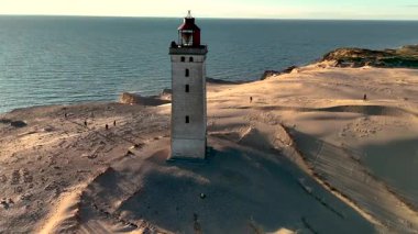 Rubjerg Knude Deniz Feneri, altın kum tepeleri ve engin denizlerle çevrili Danimarka 'nın kumlu uçurumlarında görkemli bir şekilde duruyor..