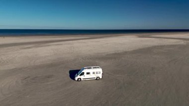 Danimarka 'nın Romo kentindeki Lakolk Strand' in engin kumlu kıyılarının tadını çıkarın. Yalnız bir karavan plajda dinleniyor, sakin okyanus manzarası ve berrak mavi gökyüzü ile çevrili, maceraya davetiye çıkarıyor..