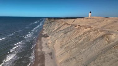 Rubjerknudde deniz feneri, Danimarka 'nın kumlu uçurumlarının üzerinde gururla durur ve aşağıdaki dalgaların nefes kesici manzarasını sunar. Bu manzaralı yer doğanın ve deniz mirasının güzelliğini yansıtıyor..