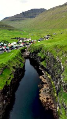 Faroe Adaları 'nın nefes kesen manzarasını keşfedin, yemyeşil kayalıkları, sakin bir nehri ve vadide yuva yapmış güzel bir Gjogv köyünü gösterin..