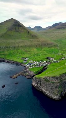 Uçurumlar ve Faroe Adaları 'ndaki derin mavi deniz arasında yuva yapmış Gjogv köyünün nefes kesici manzarası. Bu sakin manzara, doğanın güzelliklerini yakalar..