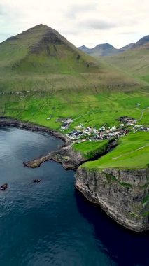 Faroe Adaları 'nın nefes kesici manzarasını keşfedin. Deniz kenarındaki Gjogv köyünü gösteren bu hava manzarası ile, yemyeşil tepeler ve engebeli uçurumlarla çevrili..