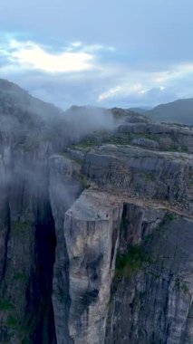 Norveç 'te Kürsü Kayası olarak da bilinen Preikestolen' in hayranlık uyandıran güzelliğini tecrübe edin. Bu görkemli uçurum, alacakaranlıkta sis ve dramatik manzaralarla çevrili huzurlu Lysefjord 'a bakıyor..