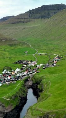 Faroe Adaları 'nın yemyeşil tepeleri arasında yuva yapmış Gjogv köyünün huzurlu güzelliğini görün. Nehir boyunca uzanan antika evler, güzel bir manzara yaratıyor..