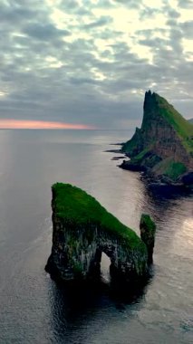 Drangarnir, Faroe Adaları 'ndaki Kuzey Atlantik Okyanusu' ndan dramatik uçurumlar gururla yükselir. Canlı günbatımı gökyüzünde sıcak renkler bırakır, büyüleyici manzarayı güçlendirir..