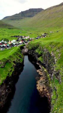 Bereketli yeşil tepeler ve Gjogv köyüyle Faroe Adaları 'nın nefes kesici güzelliğini keşfedin. Huzurlu bir nehir manzaranın içinden akar ve sakin bir atmosfer yaratır..