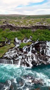 Hraunfossar şelalesi, parlak turkuaz suların ışığı yakaladığı lav tarlasında akan şelaleleri sergiliyor..