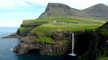 Mulafossur Şelalesi 'nin nefes kesici güzelliğini deneyimleyin. Okyanusa yuvarlanırken, açık bir günde Faroe Adaları' ndaki Gasadalur köyünün çarpıcı zeminine çarpar..
